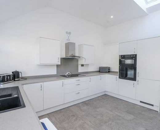 Spacious farmhouse kitchen with dining table at Ty'n Lon in Chwilog